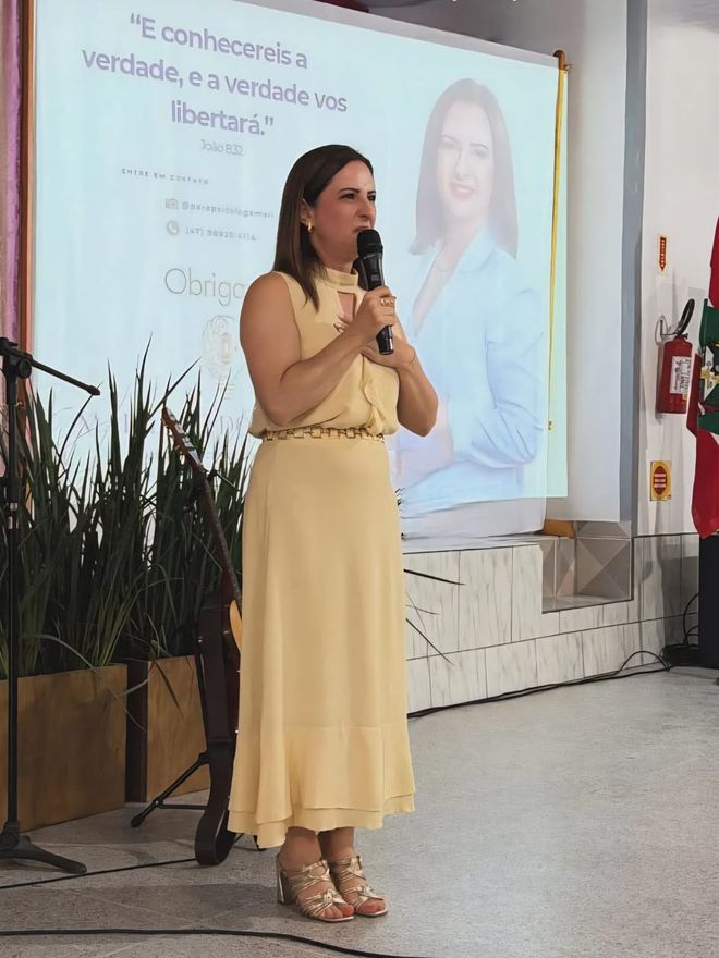 Marilene dos Santos ao microfone durante uma palestra.
